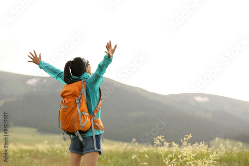cheerying young woman hiker open arms to snow mountains in the distance