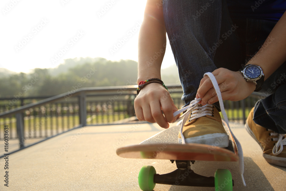 skateboarder tying shoelace at skatepark ramp