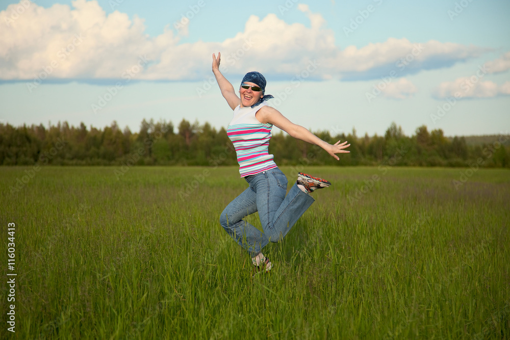 Girl in bandana jumping on a green field Girl in bandana jumping on a green field