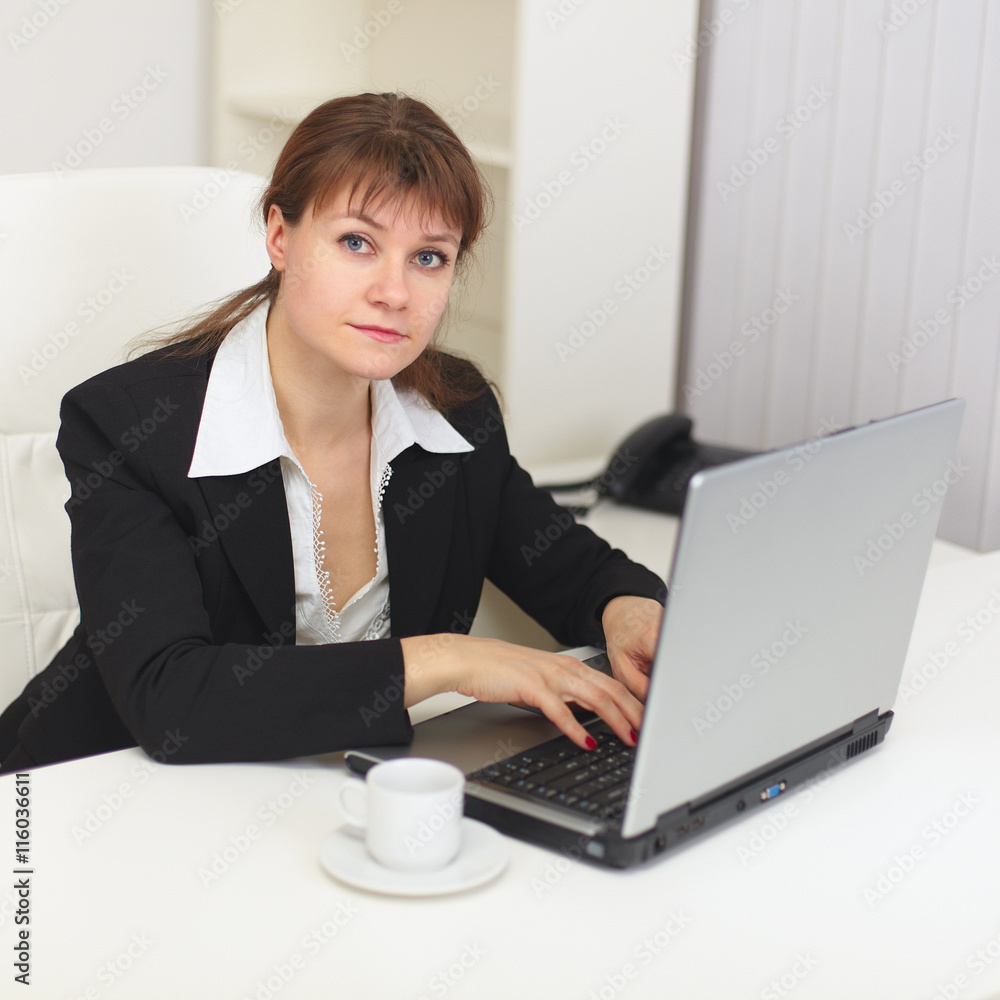 Young beautiful woman with laptop sits at a table Young beautiful woman with laptop sits at a table