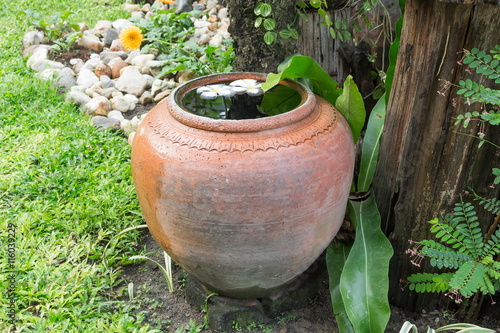 big earthen jar with grunge in the garden © pramot48