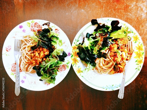 spaghetti orinji and shimeji mushroom with red oakleaf lettuce for two served on a wooden table photo