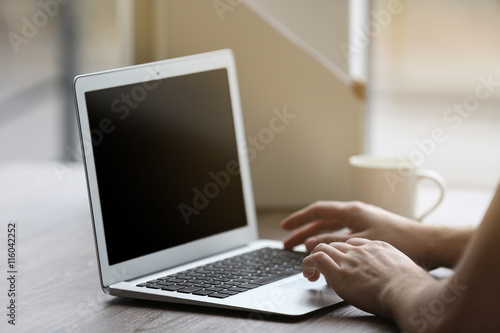 Man's hands using laptop at the table