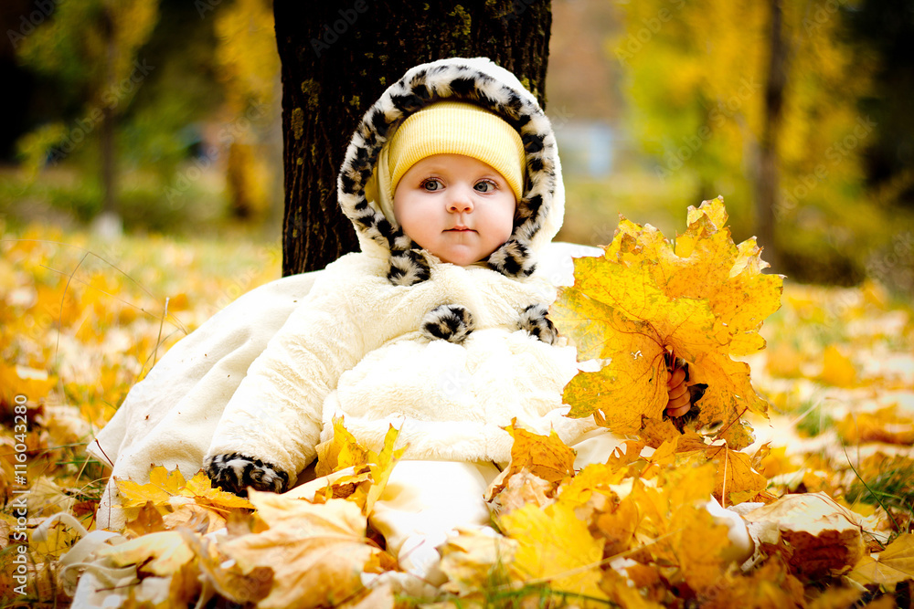 little-girl-sitting-under-a-tree-on-yellow-leaves-in-the-park-enjoying