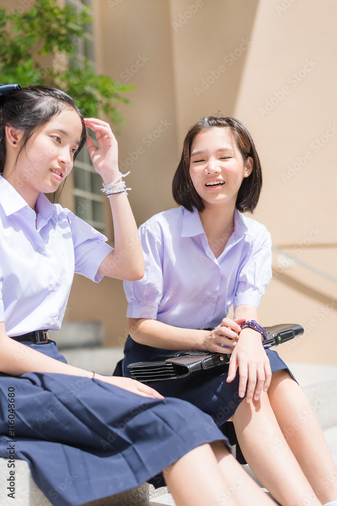 Cute Asian Thai high schoolgirls student couple in school uniform sit ...