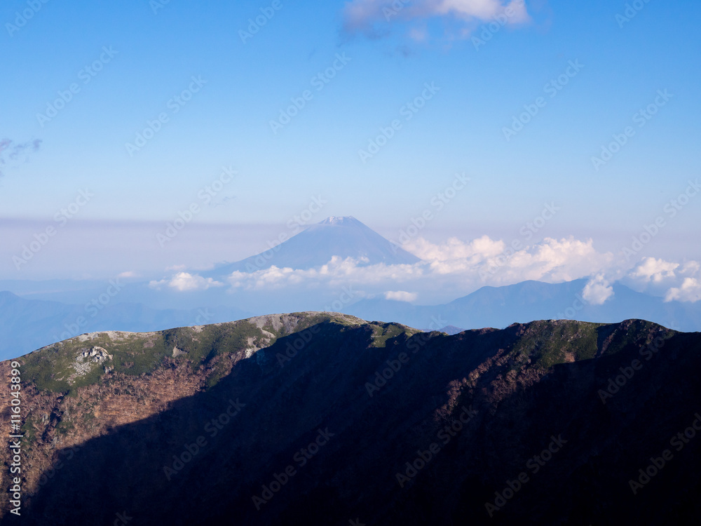 Mt.Fuji scenery at high altitude view benind the mountain ridge. Captured from Mt. Kitadake, Minami South Alps, Yamanashi Prefecture, Japan Mt.Fuji scenery at high altitude view benind the mountain ridge. Captured from Mt. Kitadake, Minami South Alps, Yamanashi Prefecture, Japan