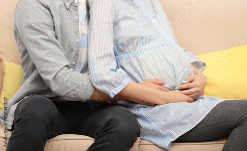 Pregnant woman and her husband on sofa at home, closeup © Africa Studio