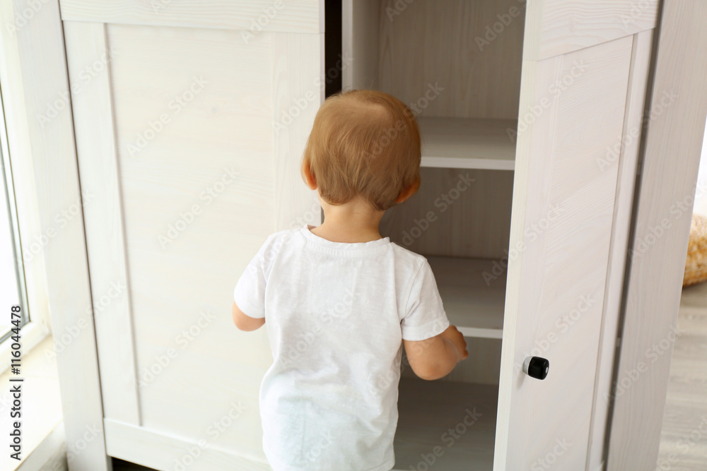 Cute baby girl playing with a wooden cupboard Cute baby girl playing with a wooden cupboard