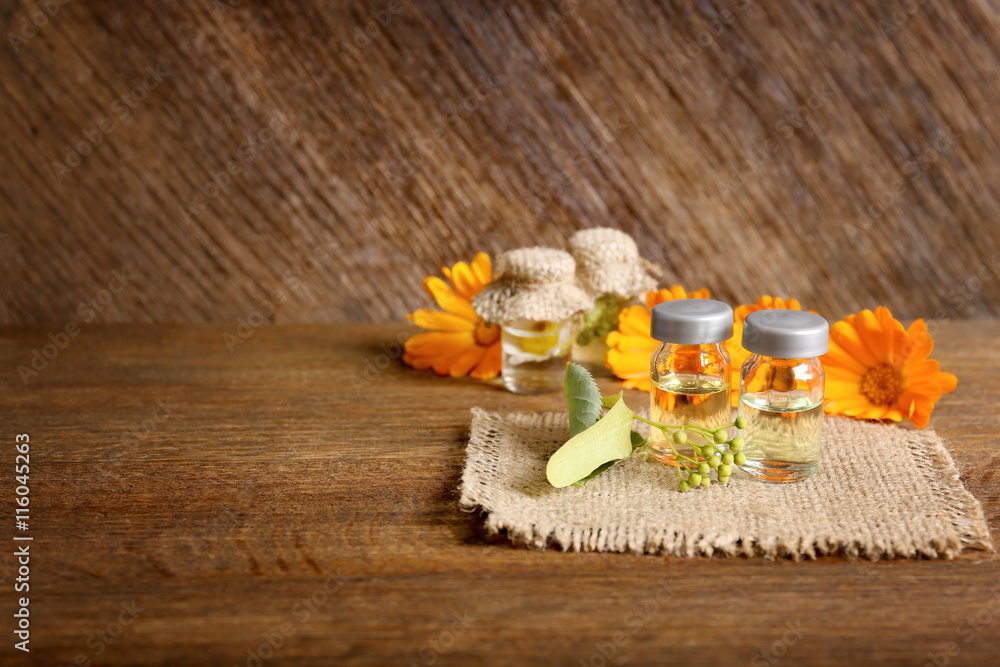 Small glass bottles and linden on wooden background Small glass bottles and linden on wooden background