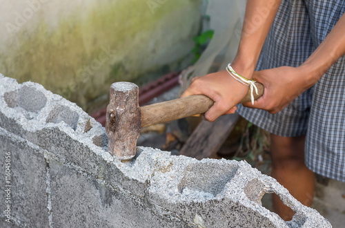 hammer in hand breaking brick Wall