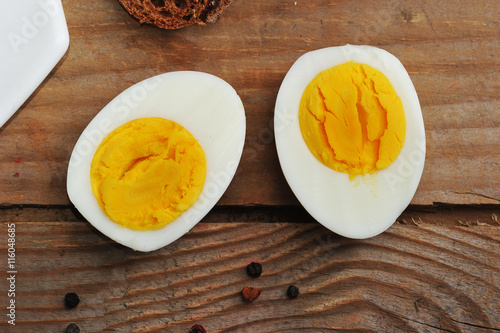 two halves of boiled eggs on wooden rustic background photo