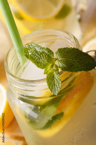 Cold lemonade with ice and mint macro in a jar. vertical 