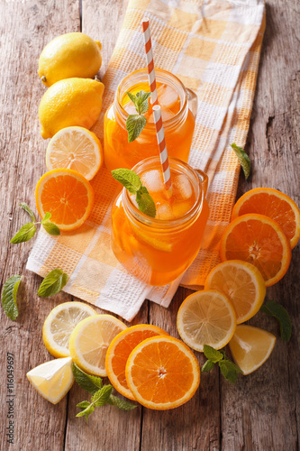 cold orange drink with lemon, mint and ice close-up. Vertical top view
