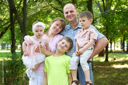 happy family portrait on outdoor, group of five people posing in city park, summer season, child and parent