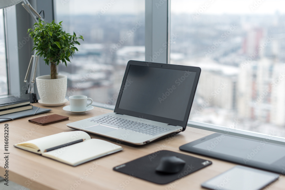 Sideview of office desktop with blank laptop and various tools. Sideview of office desktop with blank laptop and various tools.