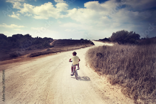 boy travels alone by bike in a desolate landscape © Cristina Conti