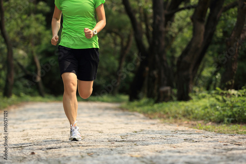 Runner athlete running on forest trail. woman fitness jogging workout wellness concept.