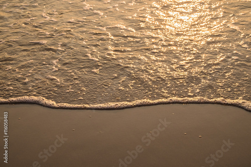 Wave on golden sand in morning photo