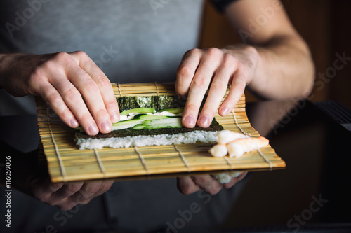 Chef rolling up sushi on a bamboo mat