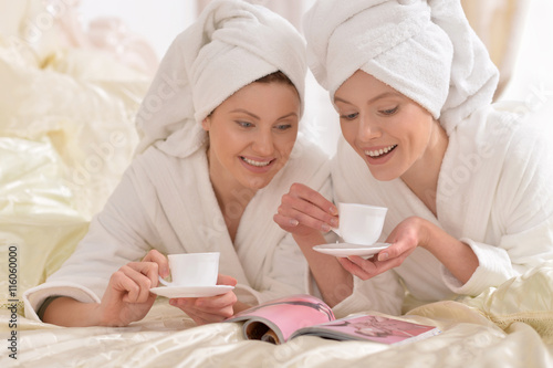 women in white bathrobes reading magazine