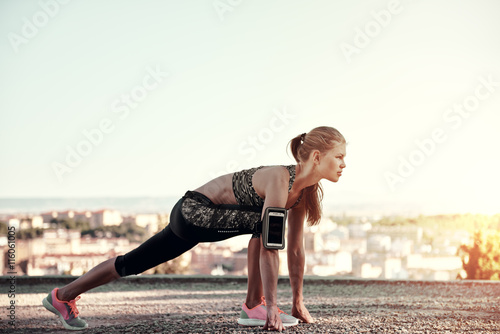 Young sporty female starting to run, standing on the track outdoors. Concept of sport, exercise and healthy lifestyle.  photo
