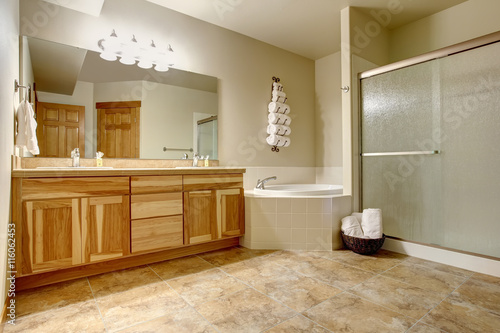 Elegant bathroom in soft tones with hardwood cabinets and marble tiled floor.