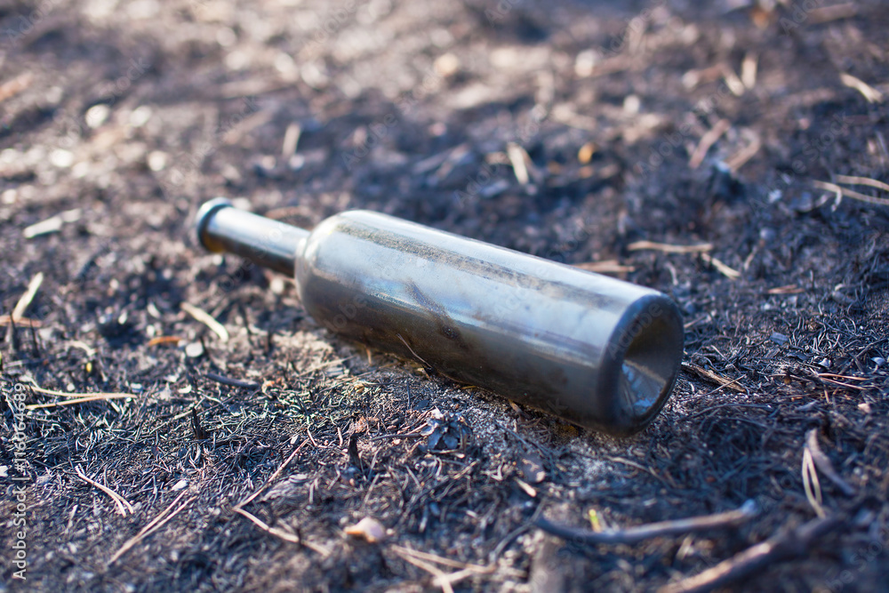 Empty brown bottle lie on the land after fire Empty brown bottle lie on the land after fire