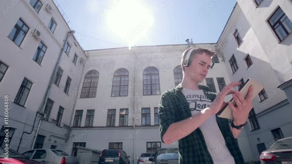 Young Man playing game on his tablet, walking around in the city Young Man playing game on his tablet, walking around in the city