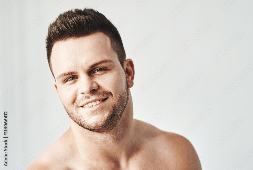 Obraz premium Handsome young man in casual white top against bright beach background