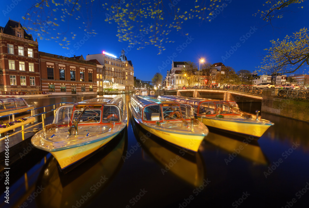 Night cityscape with traditional old houses and boats in Amsterd