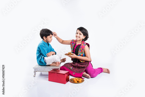 Pooja ceremony performed by cute looking sister and small brother on rakhi festival in India photo