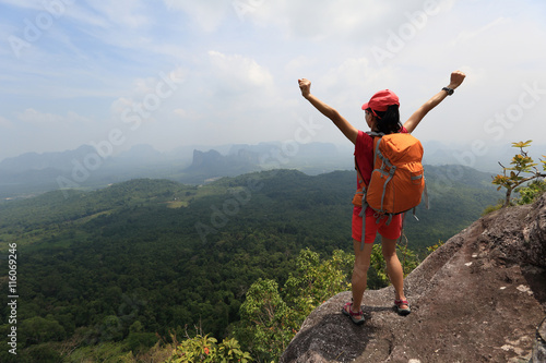 cheering successful woman hiker open arms at mountain peak