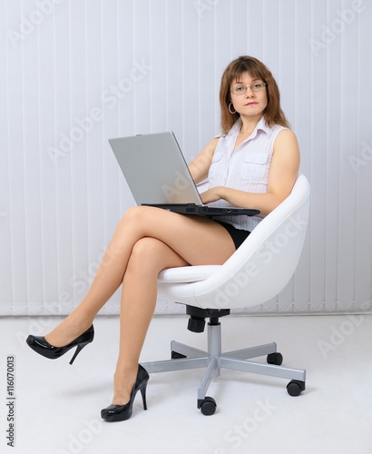 Serious, beautiful young woman sitting in a chair with laptop