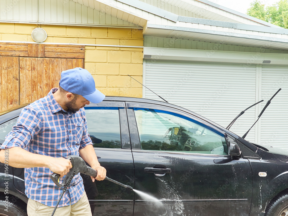 Man washing his black car near house. Man washing his black car near house.
