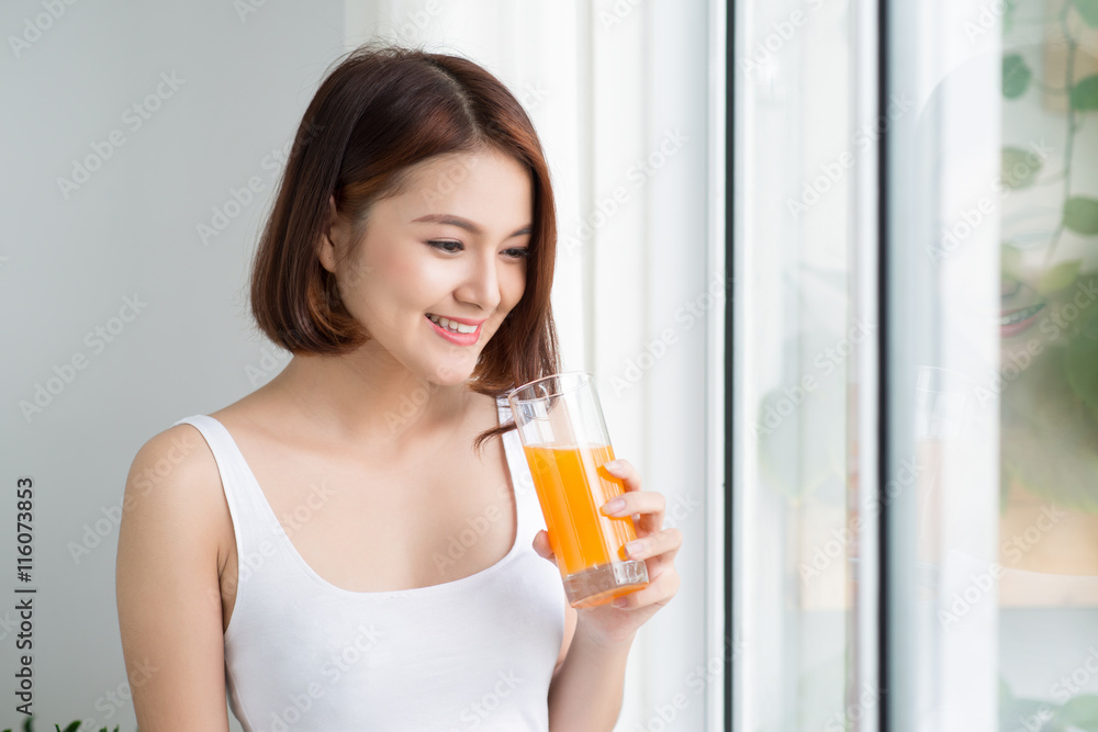 Pretty young asian woman in bright room drinking orange juice Pretty young asian woman in bright room drinking orange juice