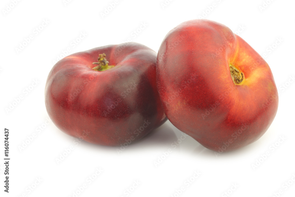Fototapeta premium two fresh wild flat nectarines on a white background