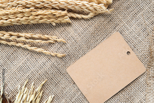 Brown paper label with rice drying on sackcloth background.