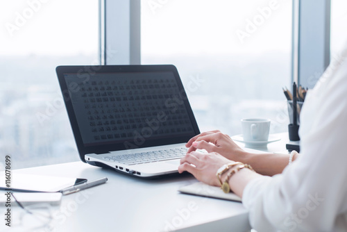Attractive female assistant working  typing  using portable computer  concentrated  looking at the monitor. Office worker reading business e-mail.