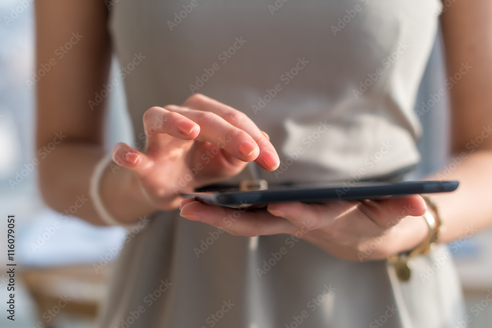 Close-up photo of a businesswoman with digital tablet in hands. Female  typing, texting and messaging, using wireless internet connection.