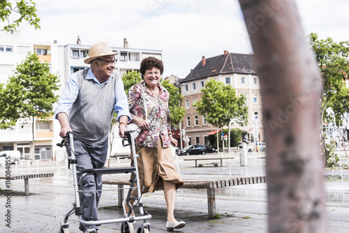 Senior man using wheeled walker for strolling with his wife