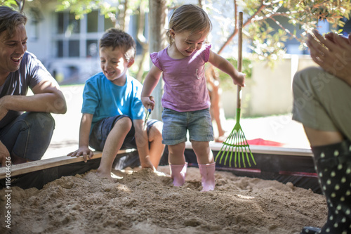 Girl with family playing in sandpit