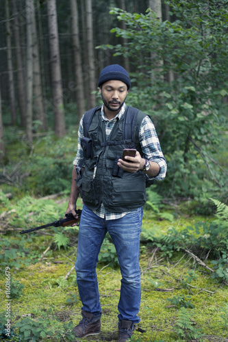Quadro su tela Interracial hunter in the forest using his phone