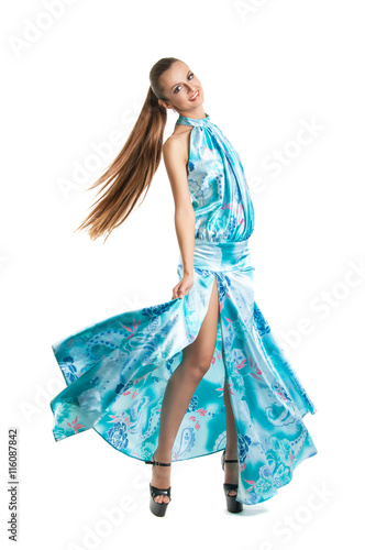 fashion portrait of a young pretty girl in a blue dress. Summer light dress fluttering in the wind, smoothly combed hair, nice smile.