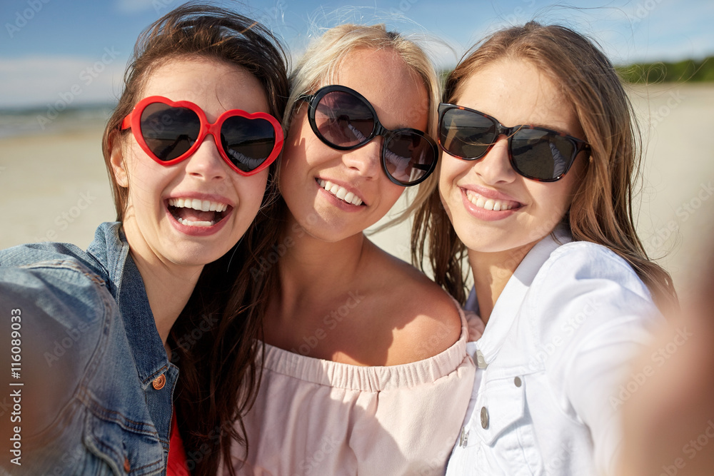 group of smiling women taking selfie on beach group of smiling women taking selfie on beach