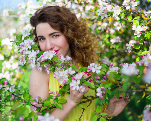 portrait of young beautiful woman smelling apple tree branch in