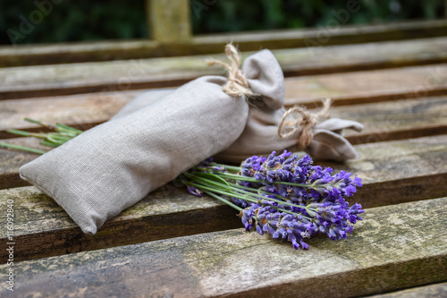 Fototapeta Naklejka Na Ścianę i Meble -  Fresh lavender flowers and canvas fragrant bag with dried lavender flowers on rustic wooden bench.