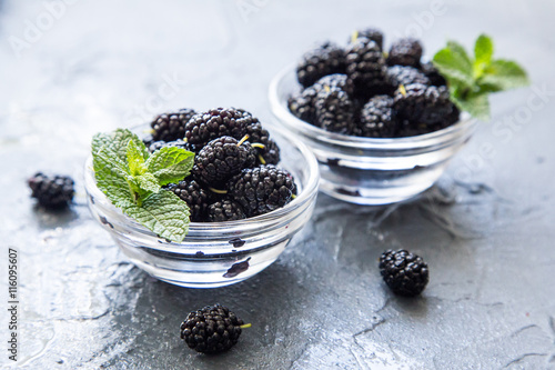 Fresh organic black mulberry in a small dessert plates with mint