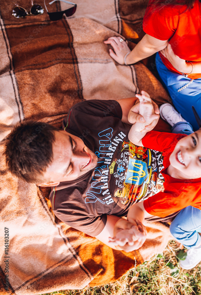 Obraz premium family resting and fun on plaid neat the lake. Summer meadow. Top view. Copy space. hand of child on eye.