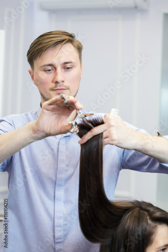 A handsome hairdresser making a haircut for brunette girl
