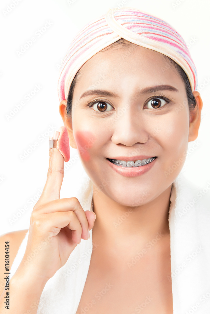 Asian woman applying foundation on face with powder puff Asian woman applying foundation on face with powder puff